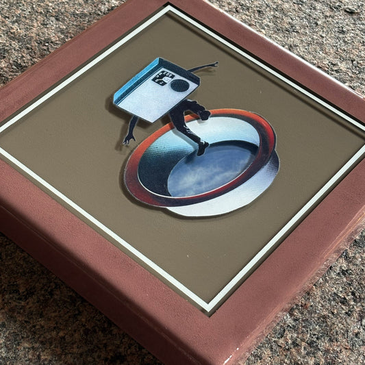 Close detail of layered collage artwork in custom epoxy resin frame.
