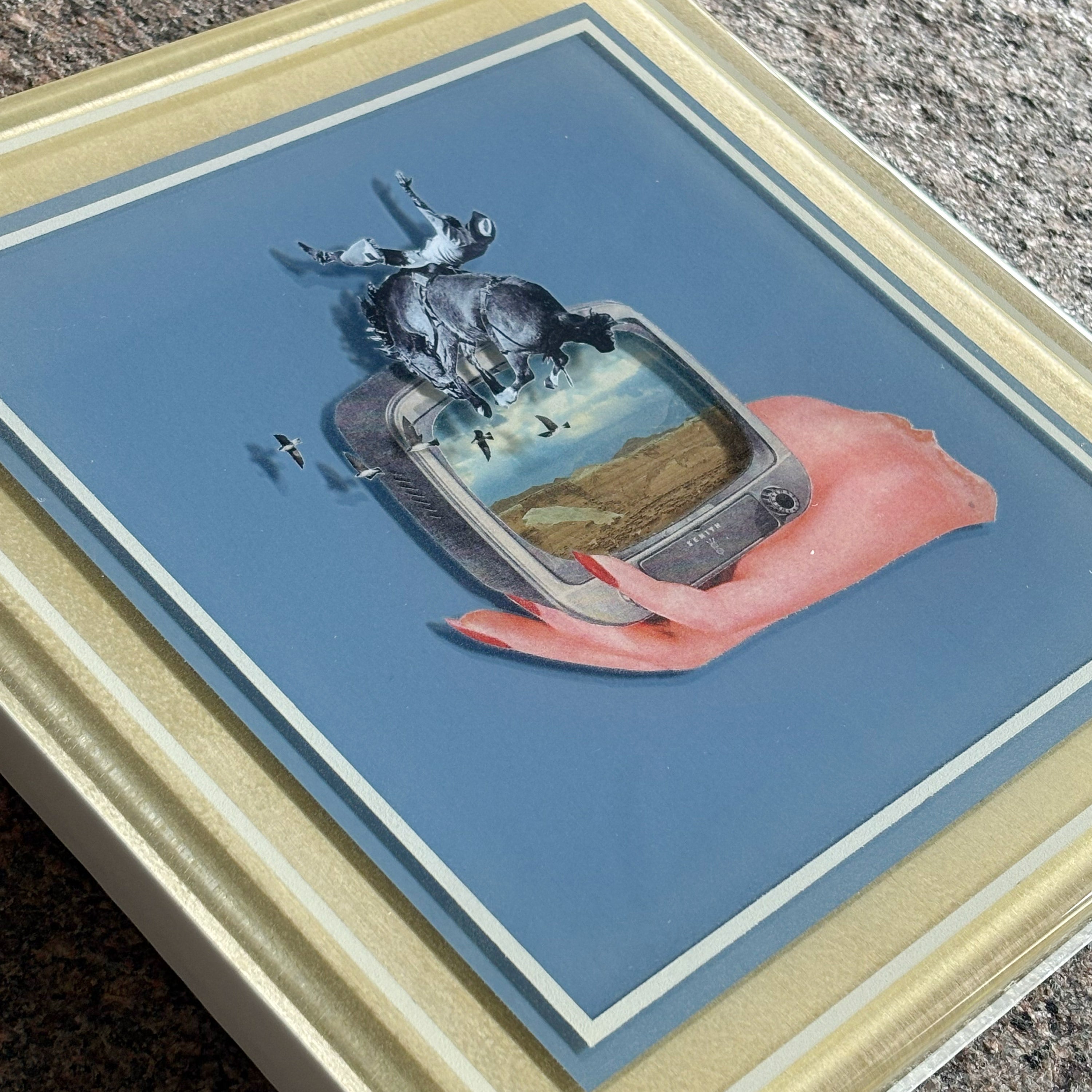 Close details of surreal artwork composition of a hand holding a television set displaying a landscape.