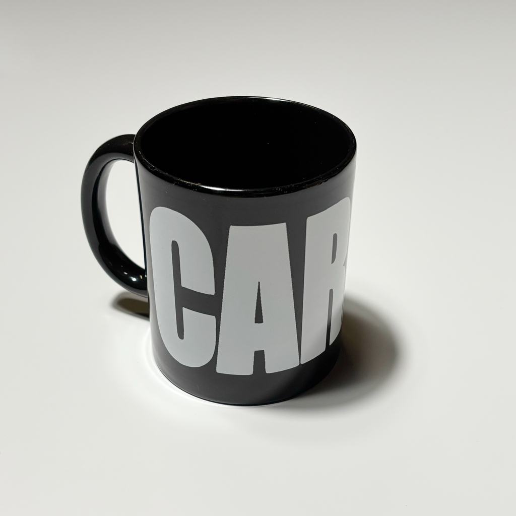 Full image of black ceramic mug.
White carpet letters.