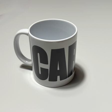 Full image of white ceramic mug.
With black carpet letters.