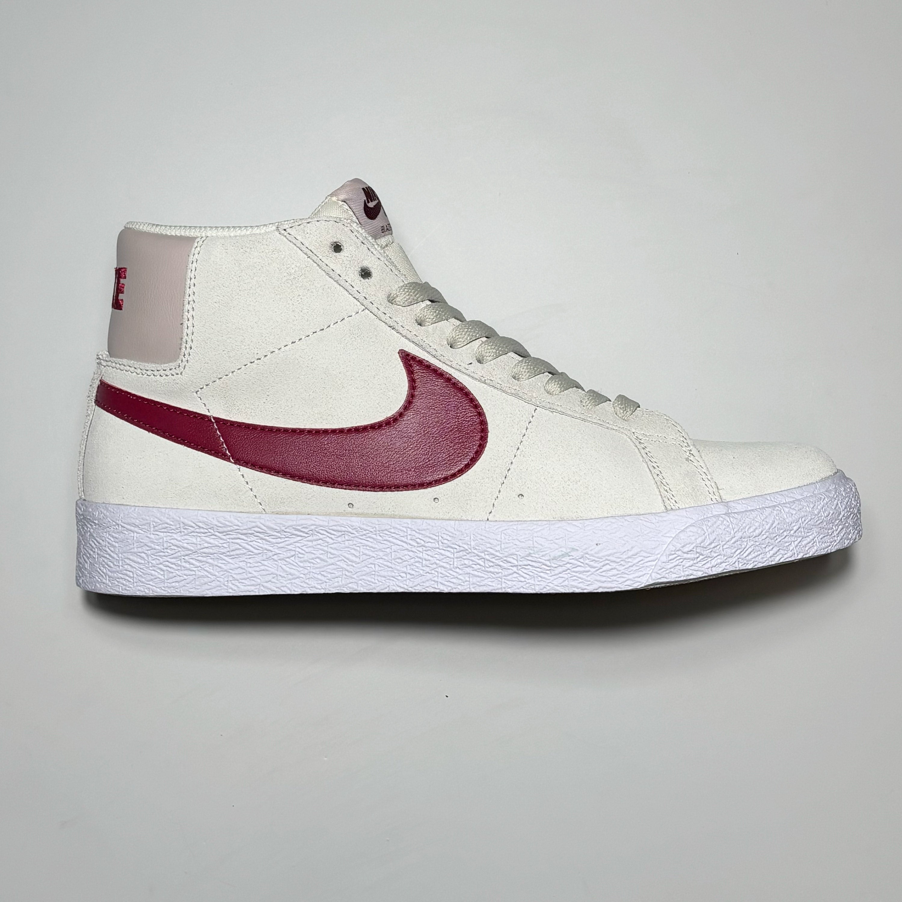 Side image of right shoe.
White suede with red swoosh.