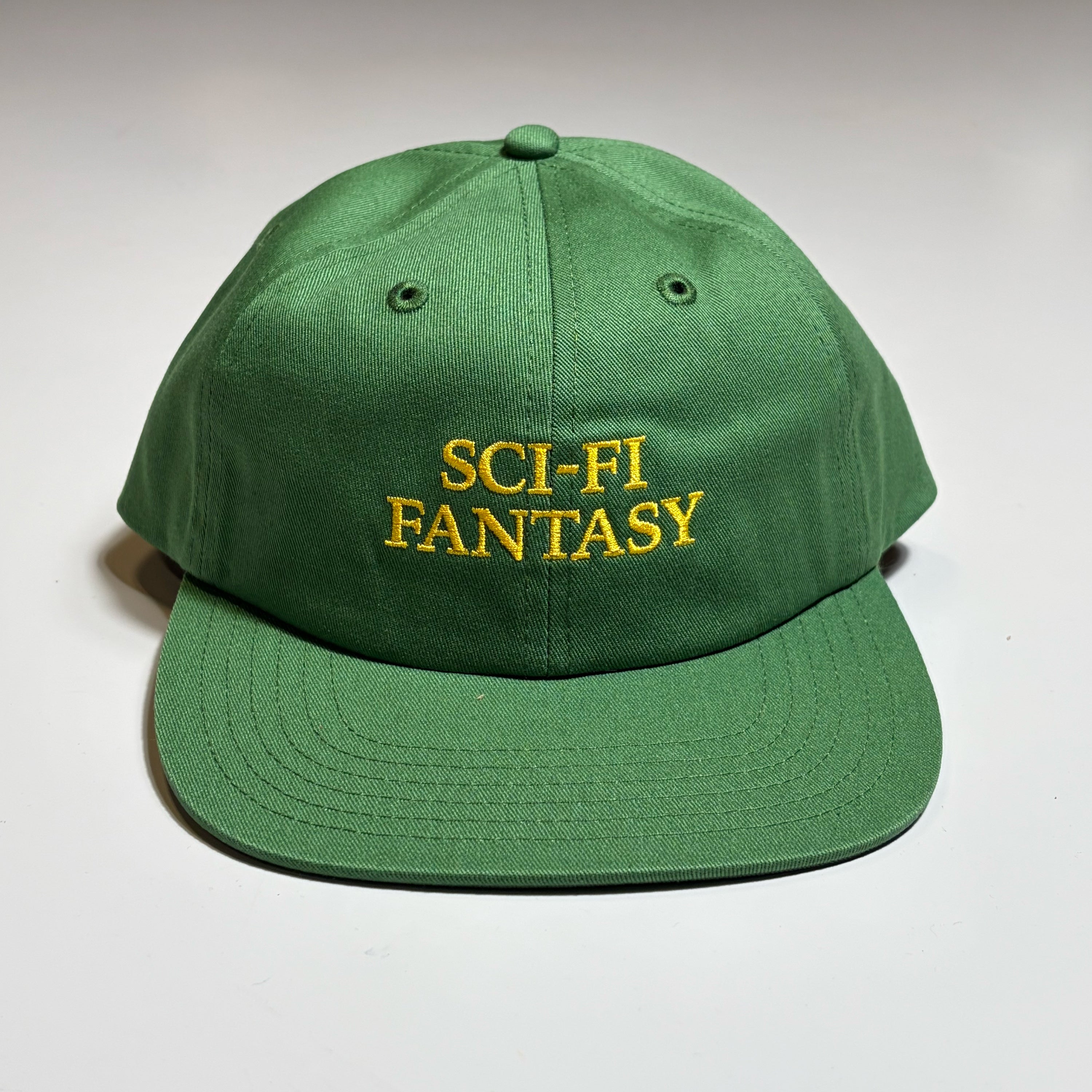 Front image of green Sci-Fi Fantasy logo hat with text embroidered in yellow on crown.