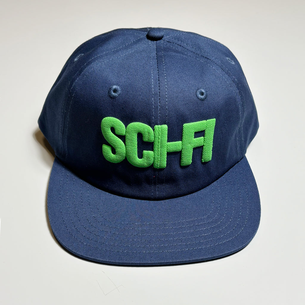 Front image of navy blue hat with green puff printed sci-fi logo on crown. 