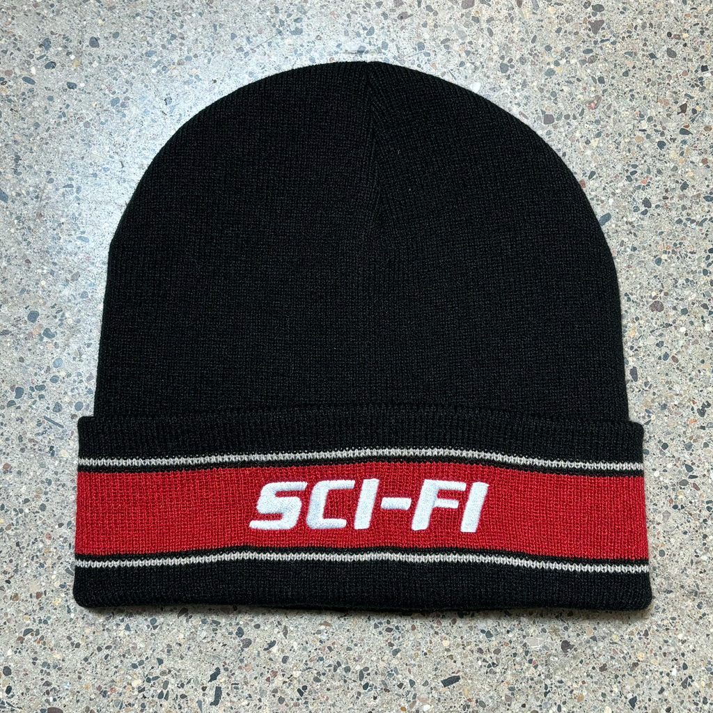 Full image of black beanie with red stripe and sci-fi logo embroidered.