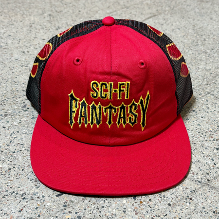 Front image of red hat with black mesh and yellow embroidered logo on crown.