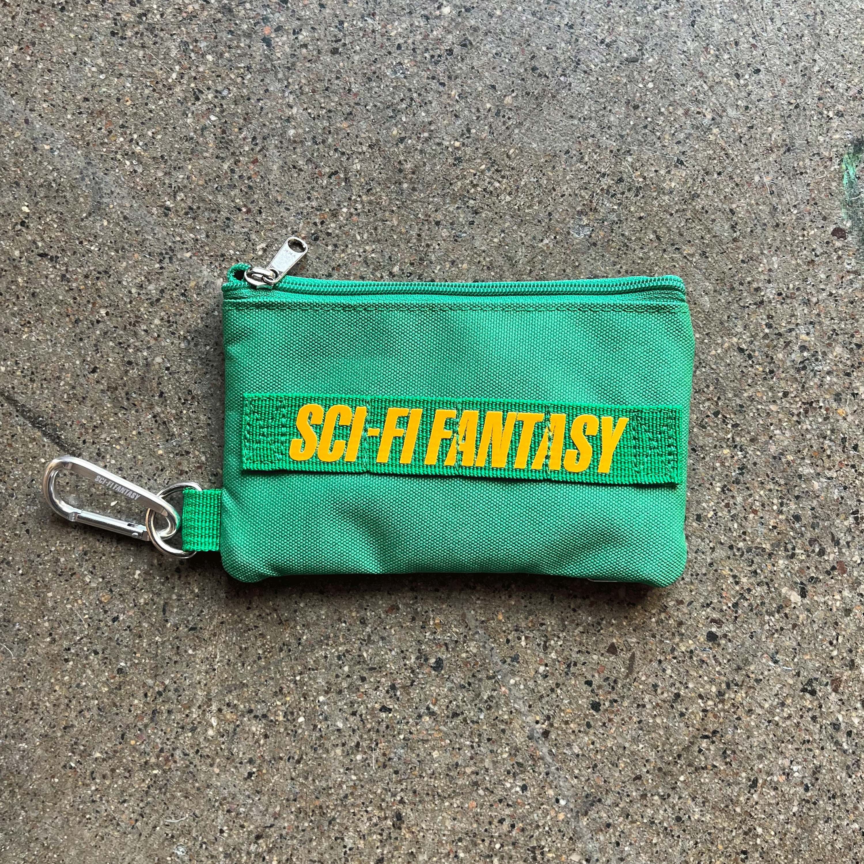 GREEN ZIP CANVAS POUCH WITH YELLOW PRINTED SCI-FI FANTASY LOGO IN YELLOW