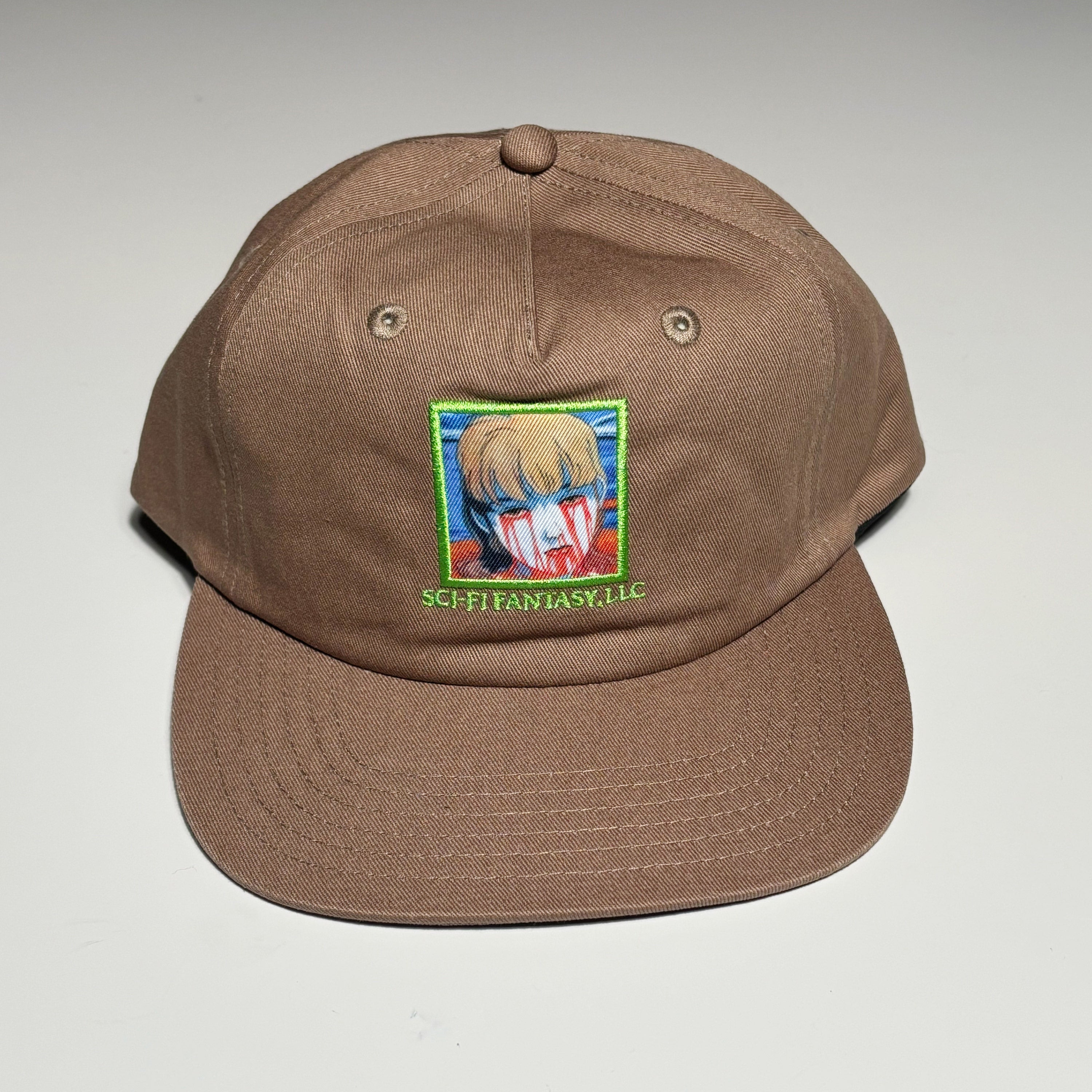 Front image of brown hat with patch artwork on crown.