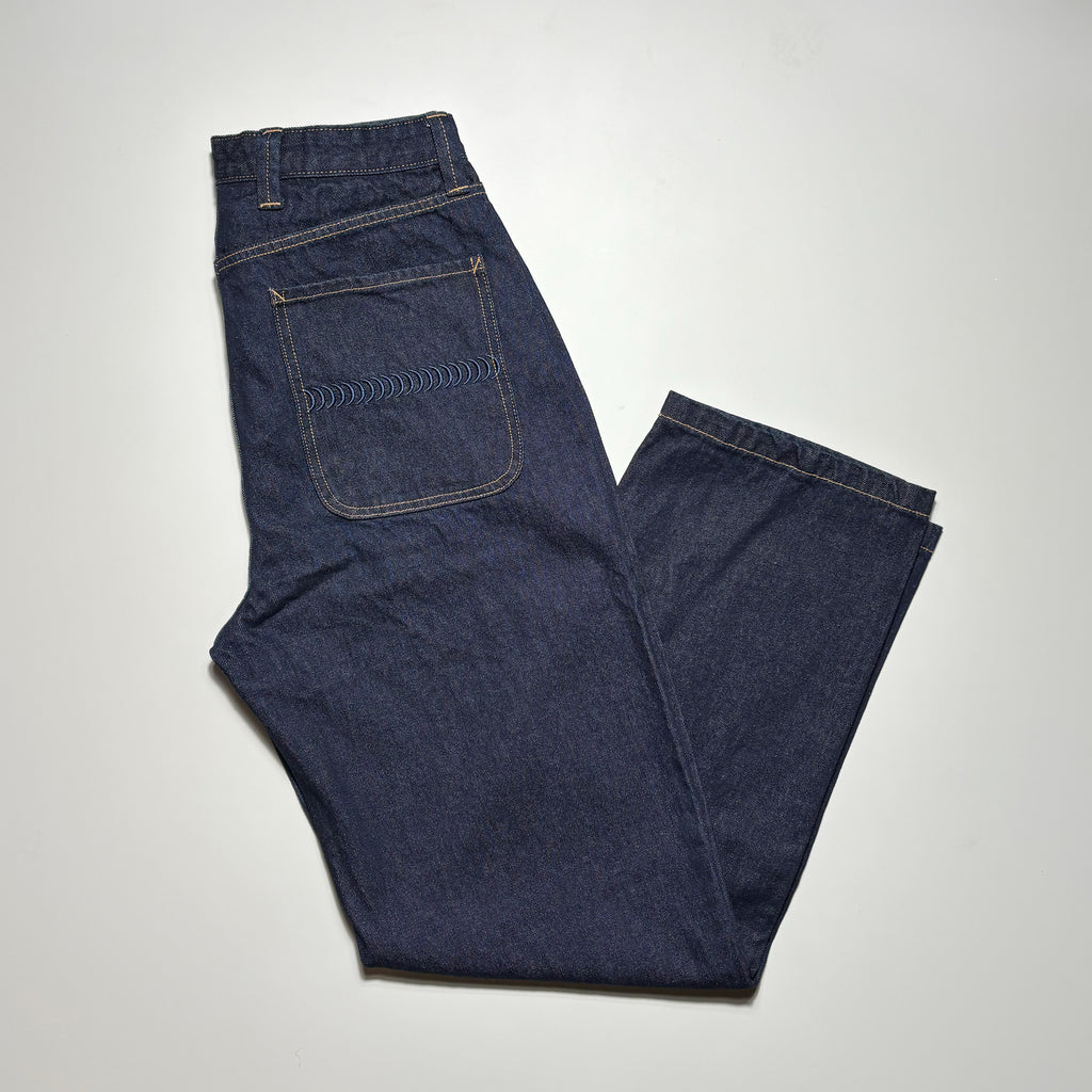 Image of folded dark blue denim. 
Gold contrast stitch and embroidered back pocket.