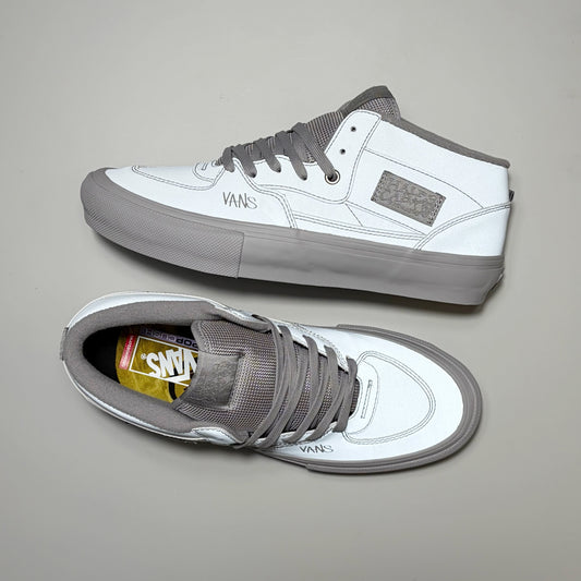 A pair of Vans Skate Half Cab mid-top sneakers in white and gray, shown from both the side and top-down views on a neutral gray background. 3M reflective material by Atiba Jefferson