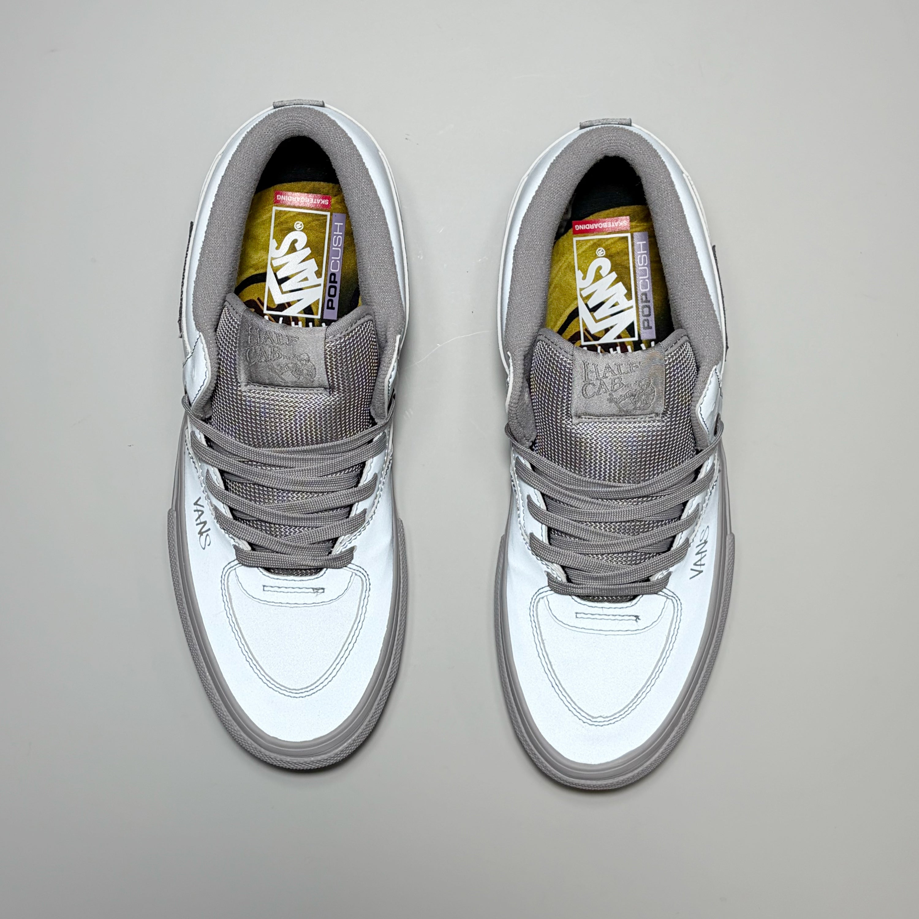 A pair of Vans Skate Half Cab sneakers in metallic silver and gray, shown from a top-down view on a neutral gray background.