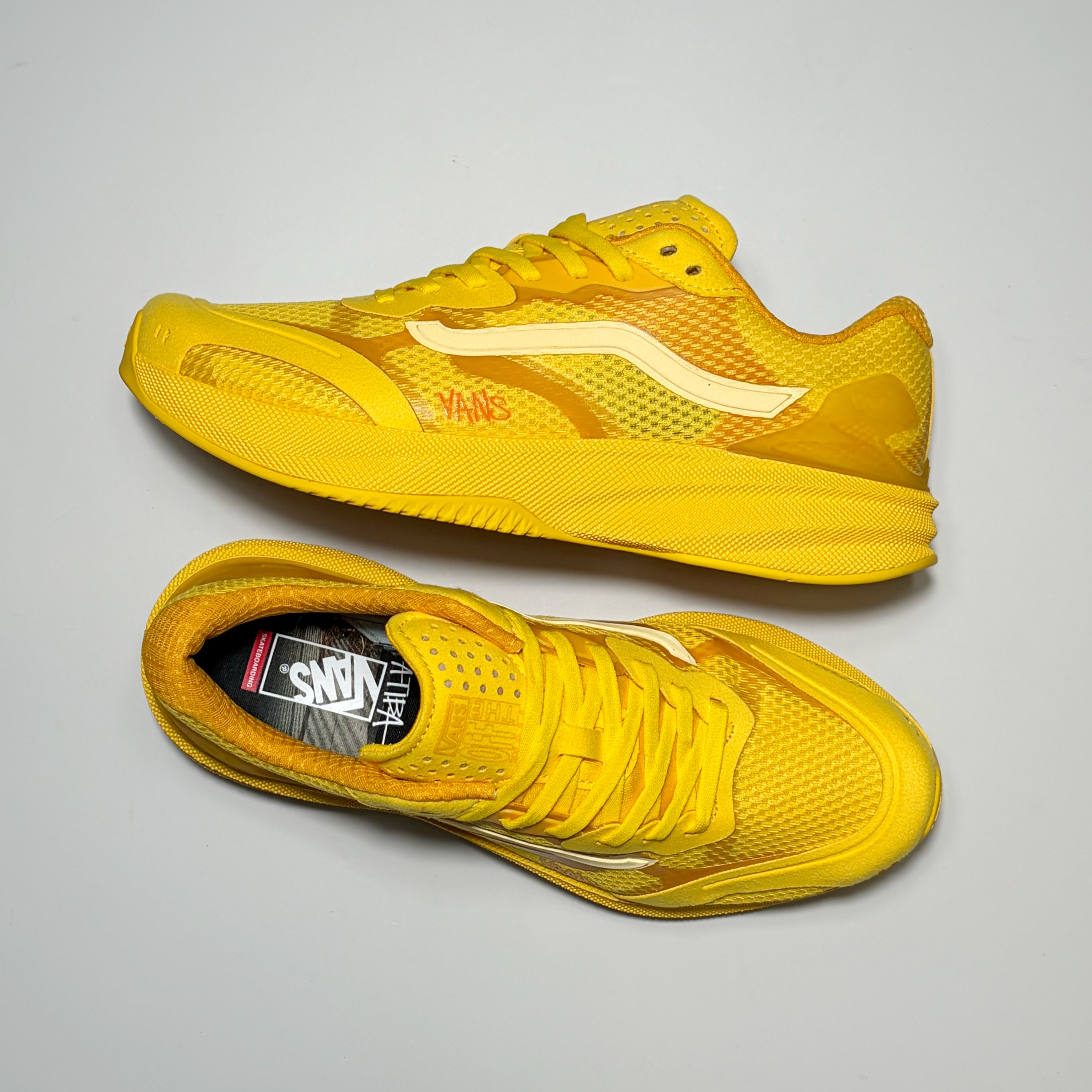 A pair of gold yellow Vans AVE Rapid LX athletic sneakers by Atiba Jefferson shown from different angles on a light gray background. The shoes feature a mesh upper, yellow laces, a thick yellow midsole, and a white wavy Vans side stripe.