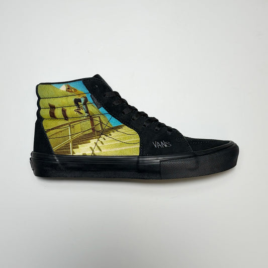 A black high-top Vans Skate Sk8-Hi sneaker featuring a graphic print of a skateboarder Geoff Rowley on a staircase on the side panel, shot by photographer Atiba Jefferson.  