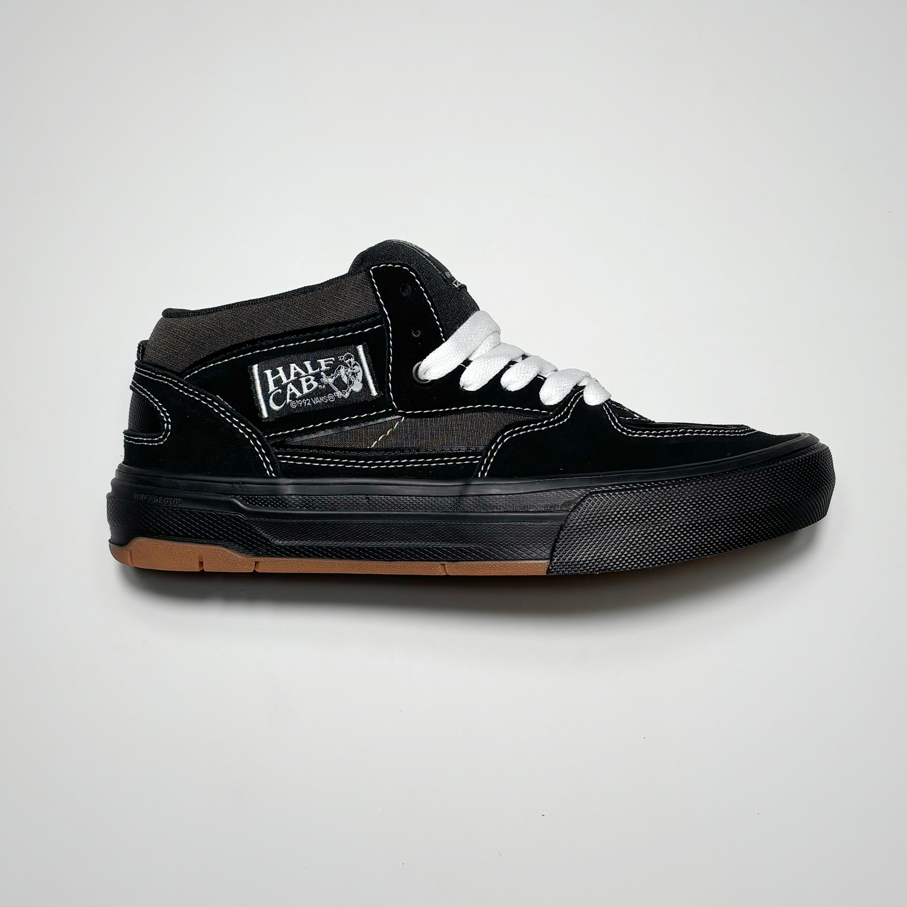 Side view of right shoe. Black suede with  black mid-sole and half cab label on heel panel.