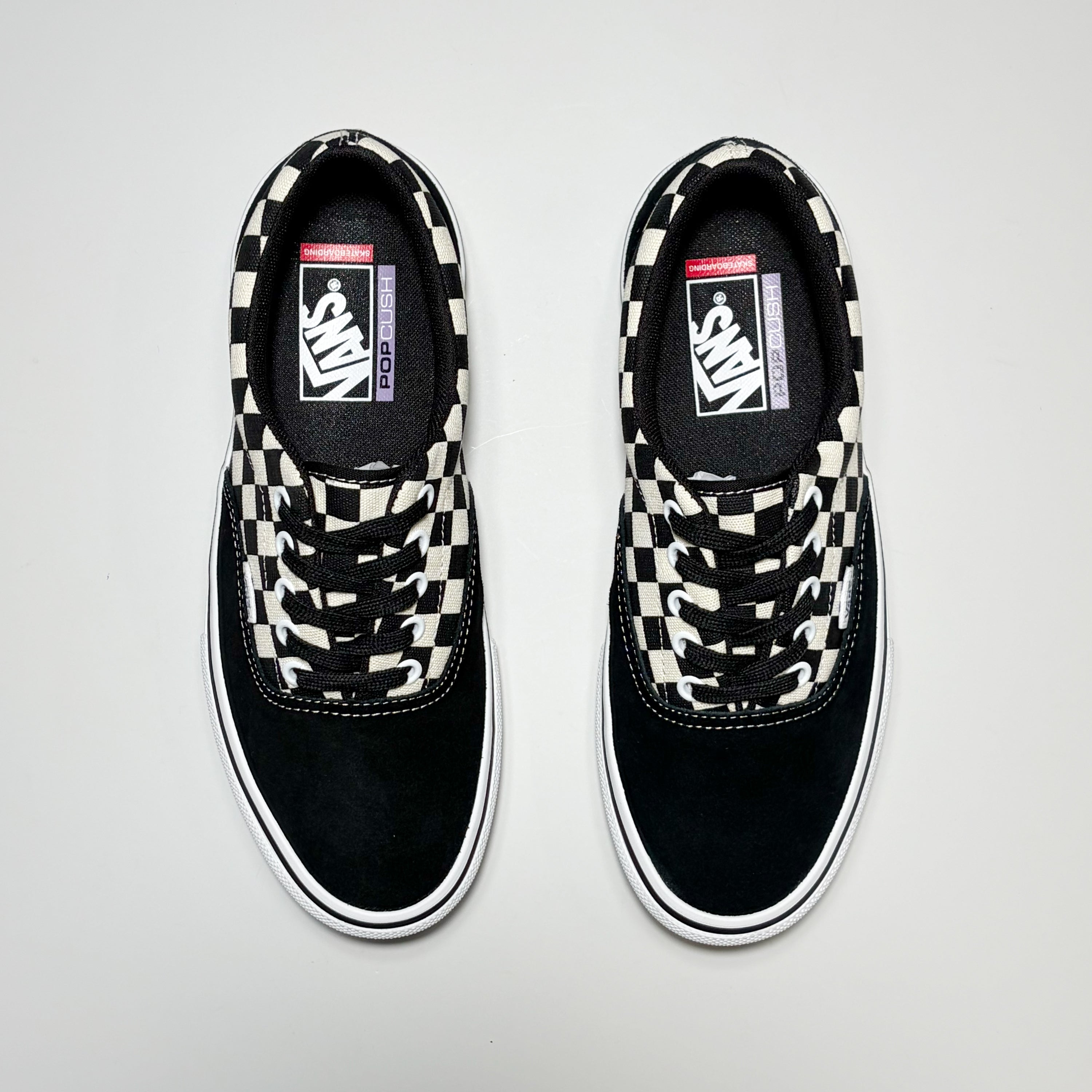 A pair of Vans Skate Era sneakers in black suede and canvas with a black and white checkerboard pattern on the laces and collar.