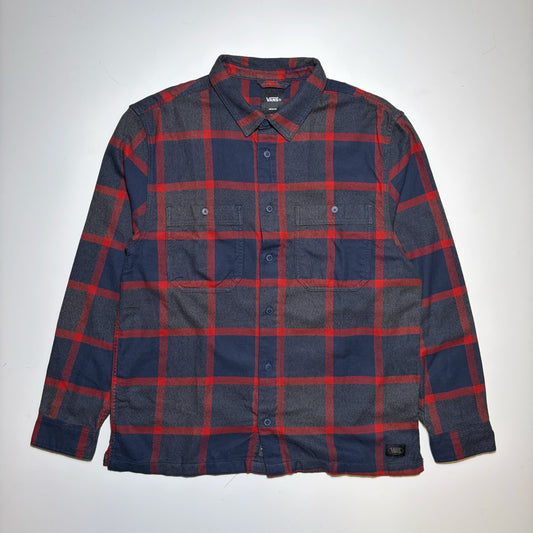 A vintage Vans button-down flannel shirt with a red and navy blue plaid pattern, laid flat against a light gray background.