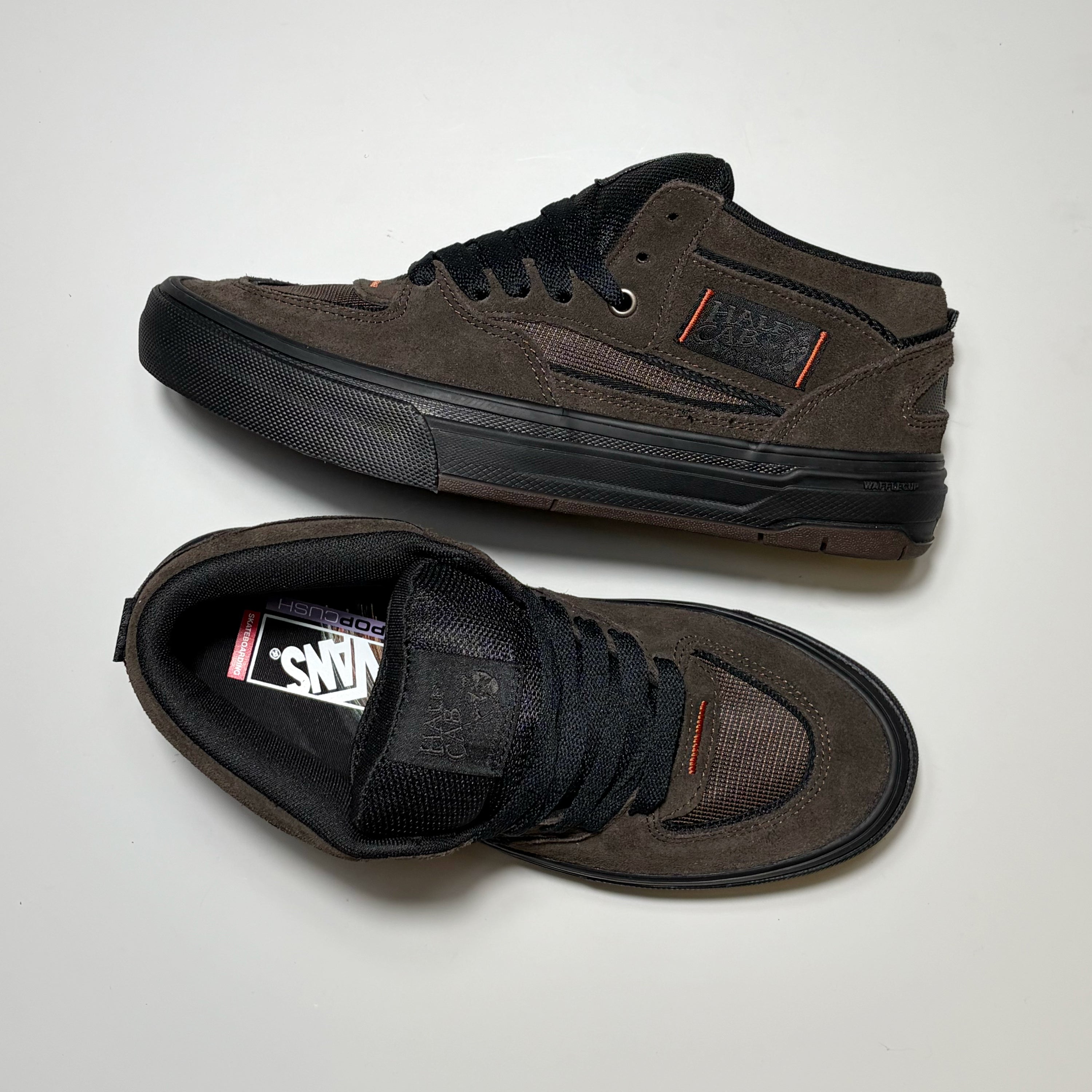 A pair of Vans Skate Half Cab Wafflecup sneakers in dark brown suede and mesh, featuring black laces, black rubber soles, and a small orange accent on the side and heel.