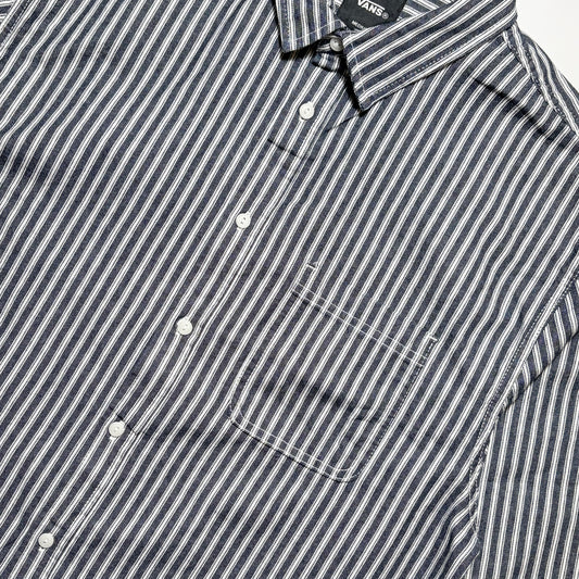Close-up of a Vans button-down shirt with navy and white vertical stripes, featuring a chest pocket and white buttons.