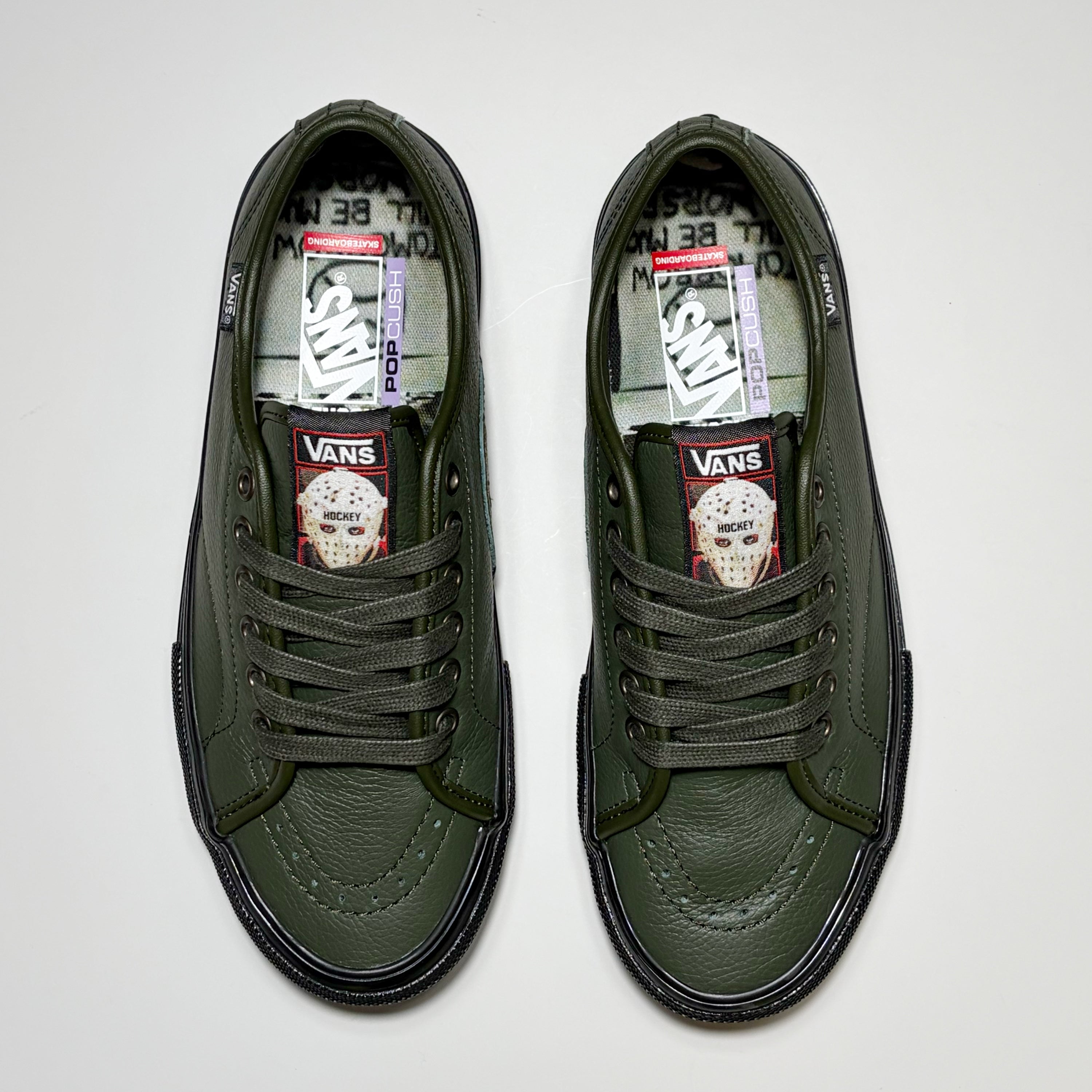Toe down view of both shoes. Green laces, custom tongue with Hockey Skateboards art.