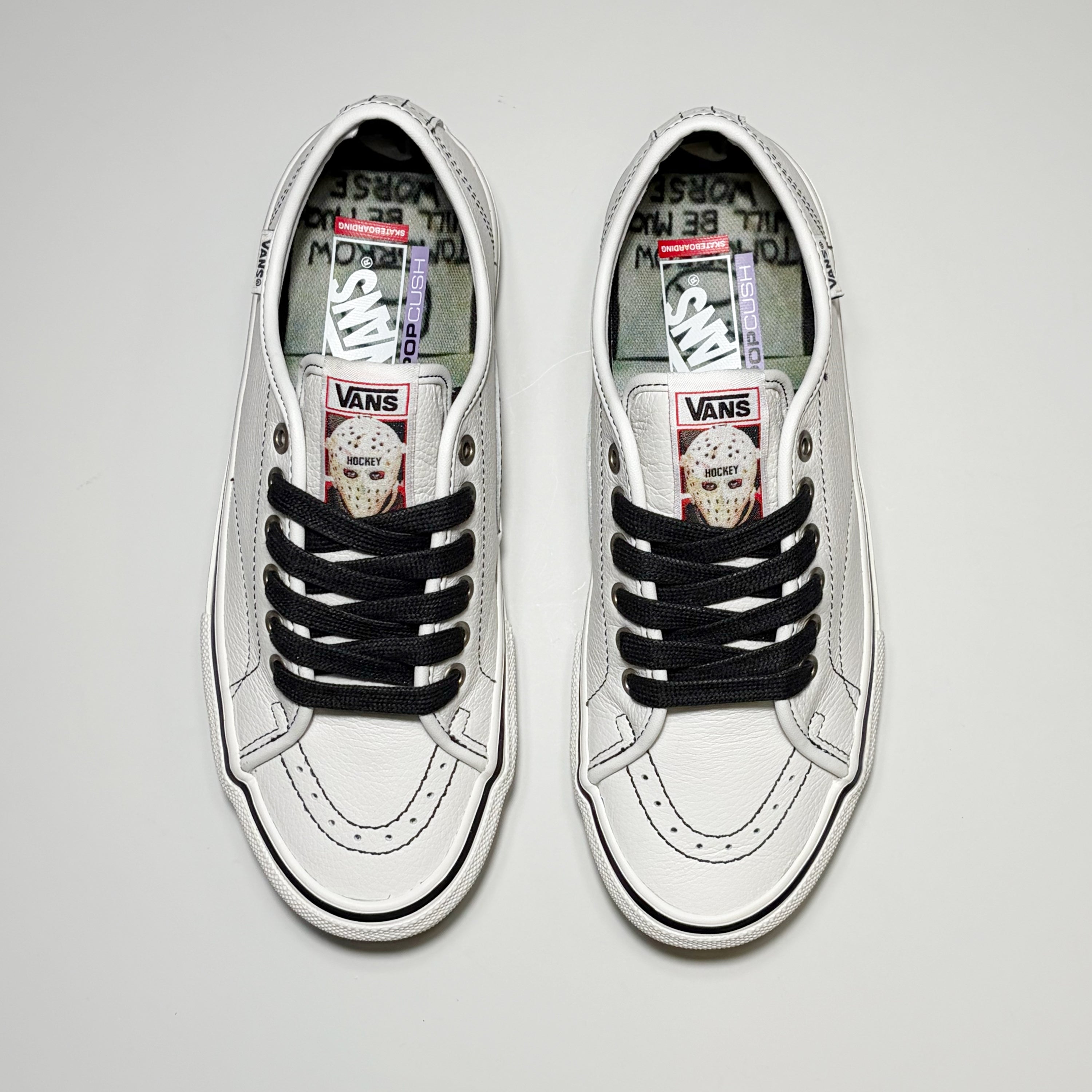 Toe down view of both shoes. Black laces, custom tongue with Hockey Skateboards art.