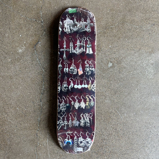 Full image of skateboard deck with photo of various earrings.