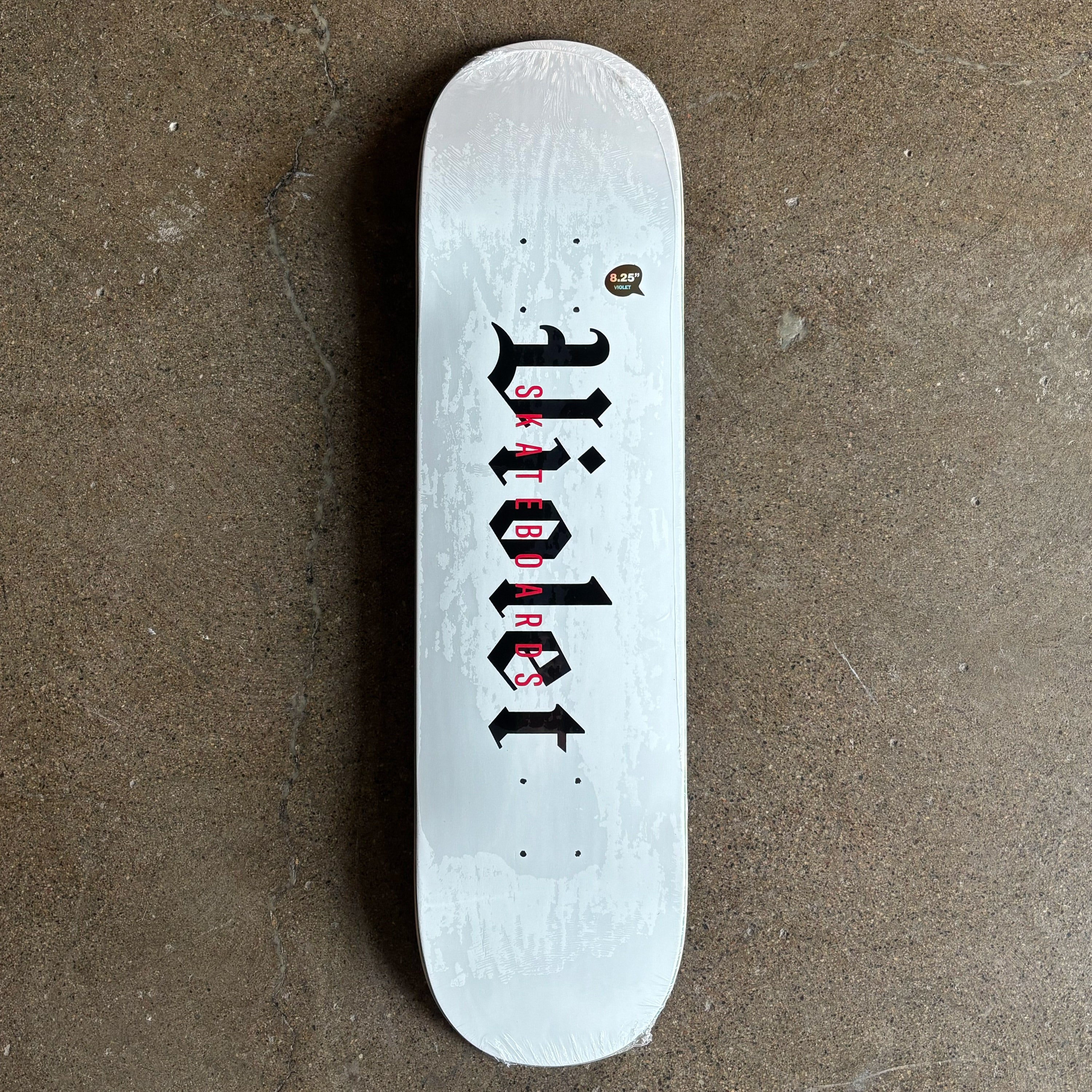 Full image of skateboard deck. White with black violet font in black.