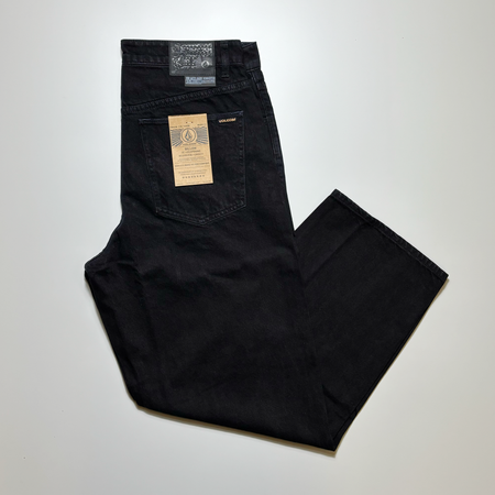 Image of black denim folded with gold volcom label.