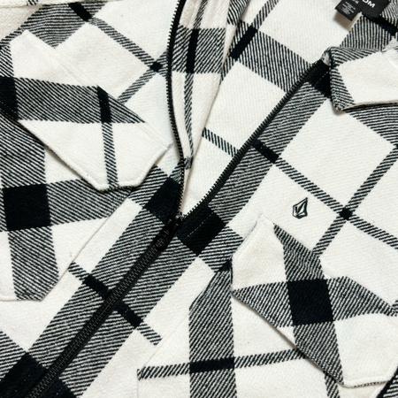 Close detail image of black/white pattern and black zipper. Volcom stone embroidered on chest pocket