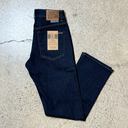 Folded image of indigo rinse denim. Gold stitching around pockets and hem. 