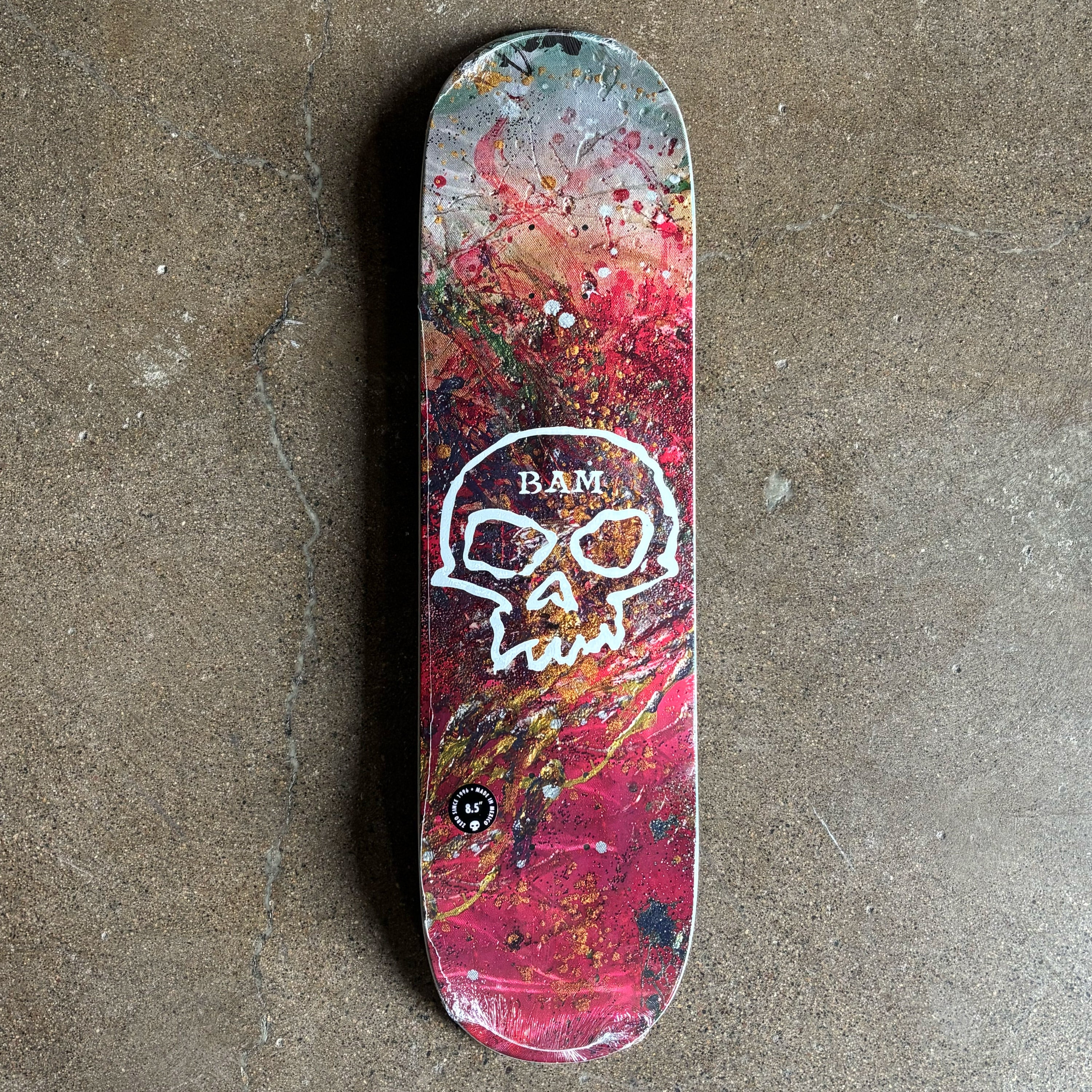 Full image of deck with colorful design and skull logo.