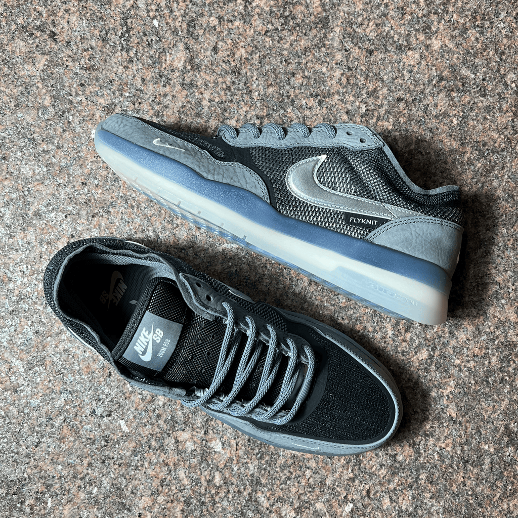 NIKE SB PS8 FLYKNIT SHOES IN COOL GREY WITH SUEDE PANELING, CLEAR SOLE AND METALLIC SWOOSH DISPLAYED ON GRANITE